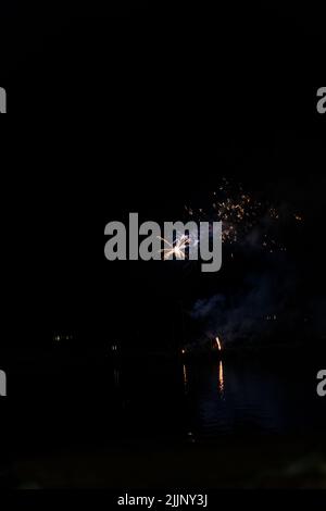 Une vue fascinante sur le feu d'artifice au-dessus de la ville et de l'eau du lac tard dans la nuit Banque D'Images