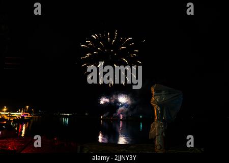 Une vue fascinante sur le feu d'artifice au-dessus de la ville et de l'eau du lac tard dans la nuit Banque D'Images