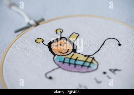 Gros plan d'une boucle de broderie avec dessin d'une abeille par un enfant Banque D'Images