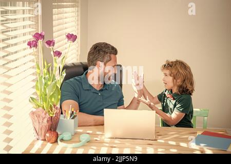 le père et l'enfant fils émerveillés à l'école travaillant en ligne sur ordinateur portable, l'ensemble Banque D'Images