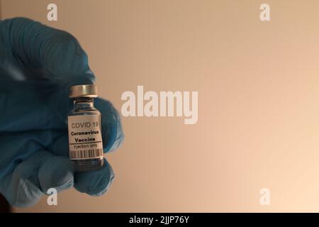 Un médecin portant des gants médicaux tient un vaccin contre le coronavirus dans sa main Banque D'Images