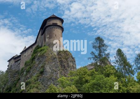 Vue sur les murs du château d'Orava. Nuages effilochés. Une colline surcultivée avec des arbres Banque D'Images