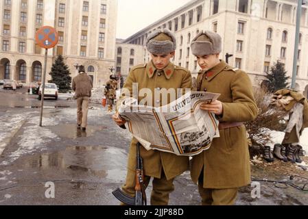 Bucarest, Roumanie, janvier 1990. Quelques jours après la Révolution roumaine, des soldats en face de 'Casa Scanteii/ Casa Presei Libere' regardant le magazine 'Universul'. 'Universul' a été publié aux Etats-Unis par A. Buhoiu pour les Roumains aux Etats-Unis il y avait une soif d'information en Roumanie, en particulier pour celui venant de l'extérieur du pays. Banque D'Images