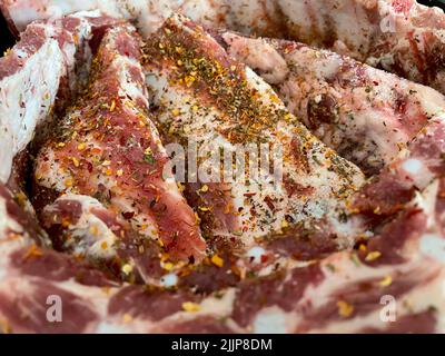 Une prise plein cadre de côtes de porc crues sur une assiette noire Banque D'Images