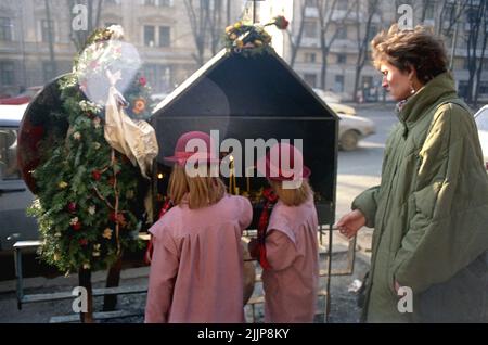 Bucarest, Roumanie, janvier 1990. Une mère et ses filles ont allumé des bougies dans le petit mémorial devant Sala Dalles pour les premières victimes de la révolution anticommuniste roumaine de décembre 1989. La mort des sept premières victimes du soulèvement a été causée par un camion de l'armée qui a frappé les manifestants. Banque D'Images