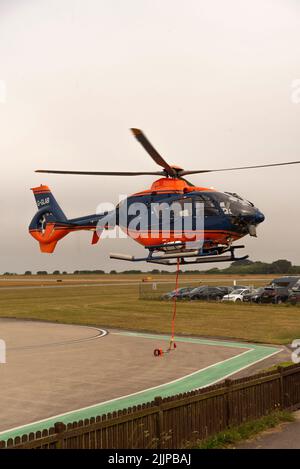 Cornwall, Angleterre, Royaume-Uni. 2022. Hélicoptère de transport aérien avec sangle de transport et porte-bagages à filet au-dessus d'un aérodrome de Cornish sur une opération de collecte et de livraison Banque D'Images