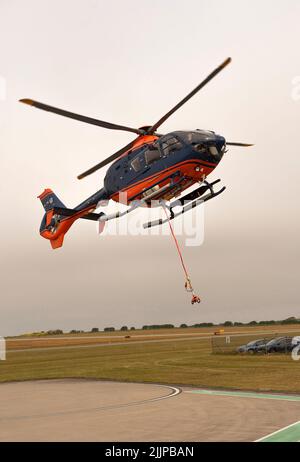 Cornwall, Angleterre, Royaume-Uni. 2022. Hélicoptère de transport aérien avec sangle de transport et porte-bagages à filet au-dessus d'un aérodrome de Cornish sur une opération de collecte et de livraison Banque D'Images