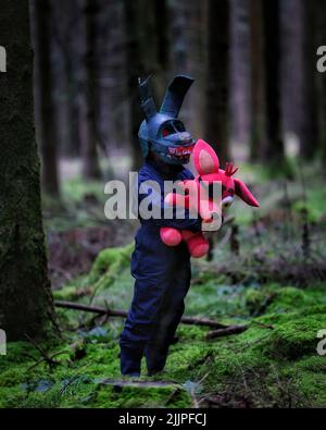 Un cliché vertical d'un homme portant un costume de lapin effrayant et tenant un lapin pirate dans sa main au milieu de la forêt Banque D'Images