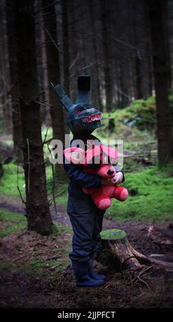 Un cliché vertical d'un homme portant un costume de lapin effrayant et tenant un lapin pirate dans sa main au milieu de la forêt Banque D'Images