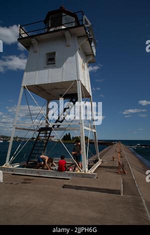 Une photo verticale d'un phare sur le brise-lames à Grand Marais, Minnesota, avec des gens autour de lui Banque D'Images