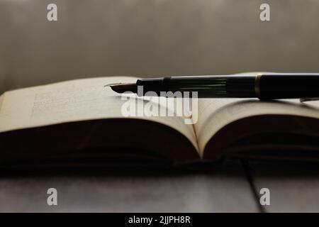 Un gros plan d'un stylo plume d'époque sur un vieux livre sur une table en bois Banque D'Images