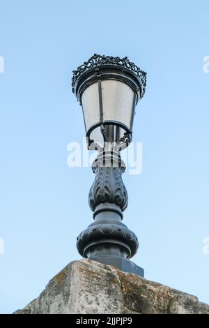 Photo verticale, à angle bas, d'une lumière de rue noire et ornementale isolée sur fond de ciel bleu Banque D'Images