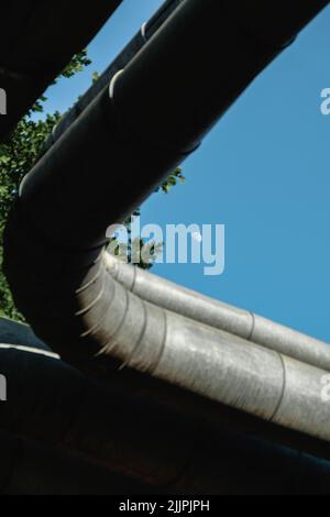 Un plan à faible angle de tubes métalliques épais avec un fond de ciel bleu et de lune Banque D'Images