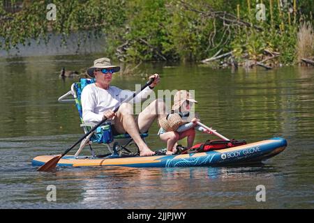 Grand-père et petite-fille flottent sur la rivière Deschutes à Bend, Oregon, sur un paddleboard essayant d'échapper à la vague de chaleur de 100 degrés F qui balaie le Nord-Ouest du Pacifique. Banque D'Images