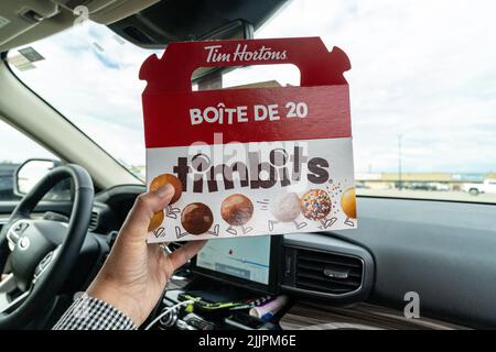 Pincher Creek, Alberta, Canada - 6 juillet 2022 : la main tient une boîte de trous de donut Timbits de Tim Horton, dans une voiture Banque D'Images