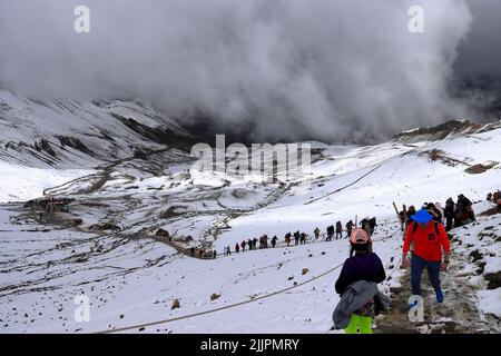 Un groupe de personnes qui randonnée à travers le paysage de neige à Vinicunca Rainbow Mountain dans les Andes du Pérou près de Cusco Banque D'Images