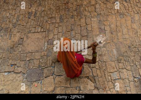 Une vue en hauteur de la femme dans sari Sweeper nettoyage de la pierre dorée sol dans la rue Banque D'Images