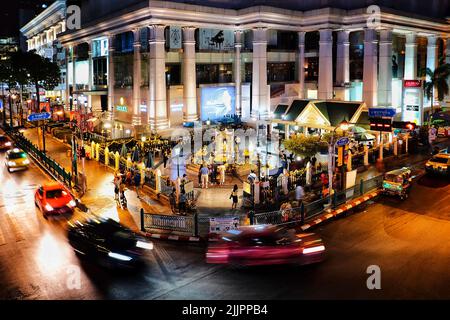 Les touristes voyageant et les voitures passant dans la rue avec une longue exposition à Erawan Shrine, Bangkok Banque D'Images