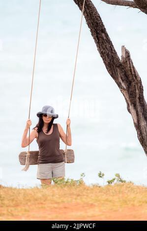 Une femme se prépare pour une balançoire en bord de mer lors d'une journée venteuse à Nhulunbuy sur la péninsule de Gove, dans le territoire du Nord en Australie. Banque D'Images