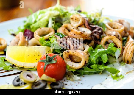 Un gros plan de salade de fruits de mer avec des légumes sur une assiette blanche Banque D'Images