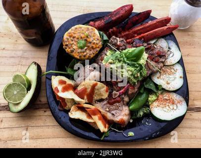 salade de pommes de terre au barbecue, filet de bœuf sec et fines herbes en gros plan sur une assiette, maracuya, chorizo, citron, avocat, chili et bière serrano, al Banque D'Images