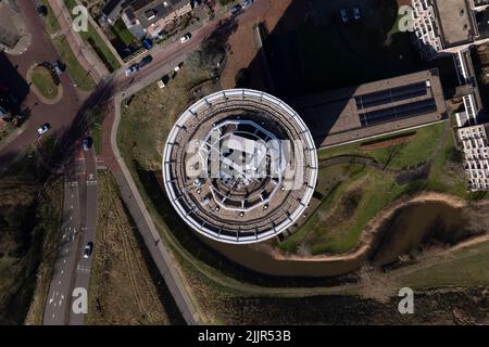 Vue de haut en bas sur la tour ronde du complexe d'appartements avec des routes et le parc qui l'entoure Banque D'Images