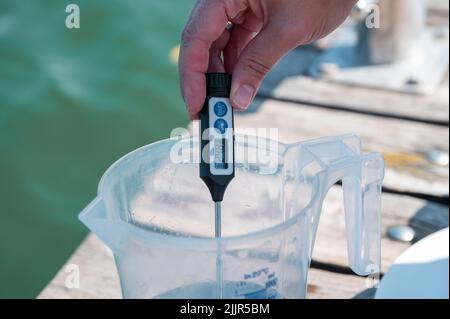 PRODUCTION - 25 juillet 2022, Bavière, Pleinfeld : Julia Wittmann mesure la température de l'échantillon d'eau prélevé en surface. Au Großer Brombachsee, Julia Wittmann du Bureau de santé du district de Weissenburg-Gunzenhausen, Section 61 - Epidemic and Environmental Hygiene, prélève un échantillon d'eau qui est ensuite analysé en laboratoire pour diverses bactéries et algues bleues, c'est-à-dire les cyanobactéries. Les vacances d'été sont presque partout en Allemagne, et la chaleur conduit les gens aux lacs de baignade. Heureusement, la qualité de l'eau est bonne presque partout. Mais comment cela est-il réellement vérifié ? (t Banque D'Images