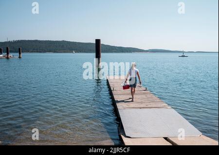 PRODUCTION - 25 juillet 2022, Bavière, Pleinfeld: Julia Wittmann marche à travers un cerf pour y prendre un échantillon d'eau. Au Großer Brombachsee, Julia Wittmann du Bureau de santé du district de Weissenburg-Gunzenhausen, Section 61 - Epidemic and Environmental Hygiene, prélève un échantillon d'eau qui est ensuite analysé en laboratoire pour diverses bactéries et algues bleues, c'est-à-dire les cyanobactéries. Les vacances d'été sont presque partout en Allemagne, et la chaleur conduit les gens aux lacs de baignade. Heureusement, la qualité de l'eau est bonne presque partout. Mais comment cela est-il réellement vérifié ? (À dpa-KORR.: 'UNC Banque D'Images