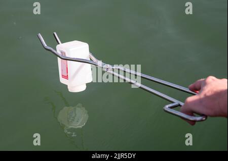 PRODUCTION - 25 juillet 2022, Bavière, Pleinfeld: En utilisant un bateau sur des pinces, Julia Wittmann prend un échantillon d'eau à une profondeur d'eau de 50 cm. Au Großer Brombachsee, Julia Wittmann du Bureau de santé du district de Weissenburg-Gunzenhausen, Section 61 - Epidemic and Environmental Hygiene, prélève un échantillon d'eau qui est ensuite analysé en laboratoire pour diverses bactéries et algues bleues, c'est-à-dire les cyanobactéries. Les vacances d'été sont presque partout en Allemagne, et la chaleur conduit les gens aux lacs de baignade. Heureusement, la qualité de l'eau est bonne presque partout. Mais comment est-ce que c'est vraiment vérifier Banque D'Images