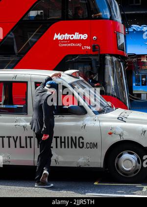 Une photo d'un chauffeur de taxi qui se penche sur un taxi en arrière-plan d'un bus rouge à impériale Banque D'Images