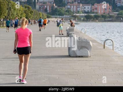 La femme portant un haut et un short de sport rose, marchant sur la promenade du front de mer à Koper, Slovénie Banque D'Images