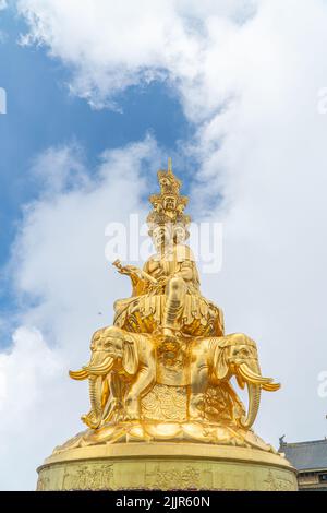 Un gros plan vertical d'une statue de Bouddha doré sur fond bleu ciel nuageux Banque D'Images