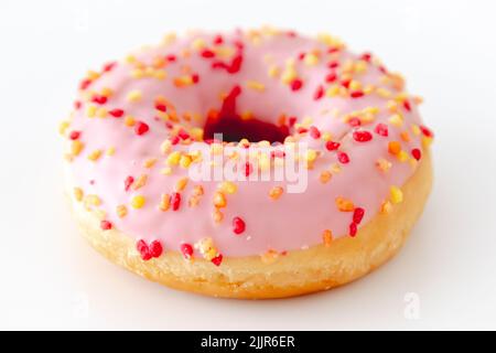 Gros plan d'un donut rose entier avec des saupoudres isolées sur un fond blanc Banque D'Images