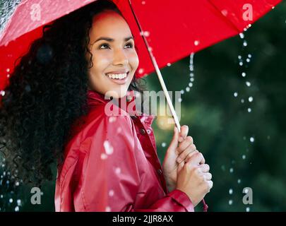 Sa pluie, son versement. Une belle jeune femme debout sous la pluie avec un parapluie. Banque D'Images