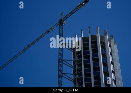 Tour grue en action construction d'un nouveau bâtiment rond de plusieurs étages Banque D'Images