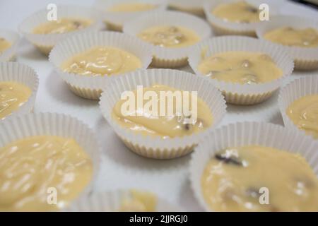 Étuis en papier remplis de pâte à muffins Banque D'Images