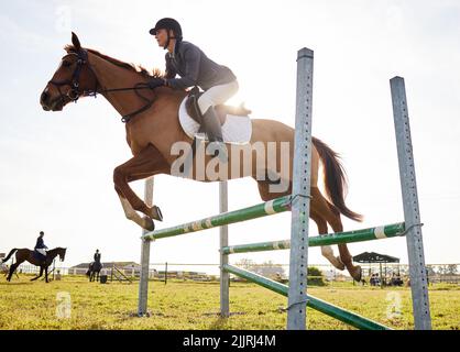 Les chevaux nous prêtent les ailes que nous manquons. Un jeune cavalier sautant sur un obstacle sur son cheval. Banque D'Images