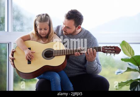 Mon super-héros personnel est mon père qui apprend à sa fille à jouer de la guitare à la maison. Banque D'Images