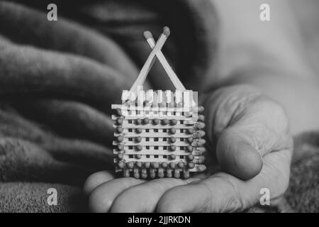 Une petite maison de match entre les mains d'une vieille femme, une maison faite maison de allumettes Banque D'Images