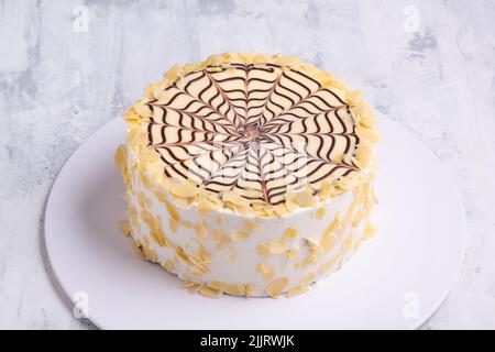 Un gâteau fait avec des couches de pâte feuilletée remplie de crème fraîche et d'araignée au chocolat sur une plaque blanche sur une surface en marbre blanc Banque D'Images