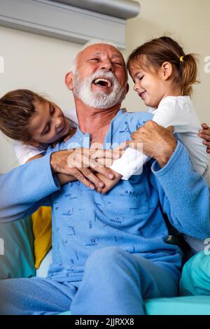 Le grand-père heureux se remet du coronavirus est visité par ses petits-enfants Banque D'Images