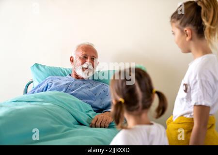 Le grand-père heureux se remet du coronavirus est visité par ses petits-enfants Banque D'Images