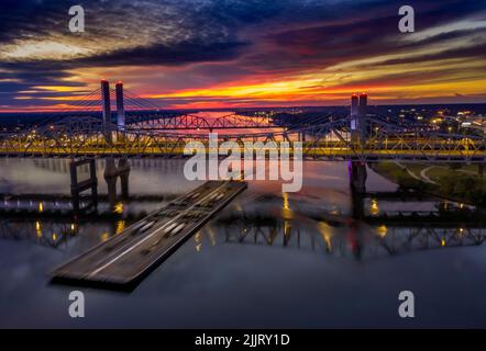 Une vue d'ensemble d'une barge de rivière naviguant sous un pont dans la rivière Ohio au lever du soleil, Louisville, Kentucky, États-Unis Banque D'Images