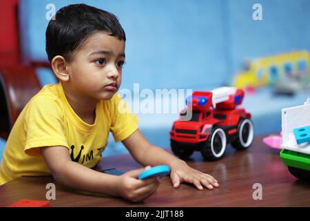 Une belle photo d'un petit enfant indien jouant avec ses jouets Banque D'Images