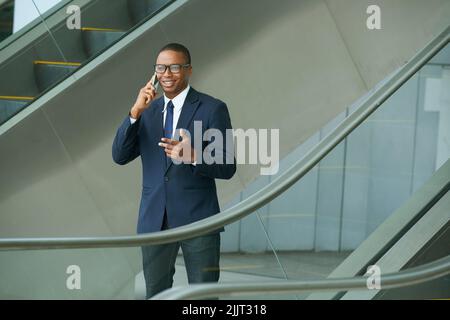 Joyeux jeune homme d'affaires dans des lunettes appelant au téléphone Banque D'Images