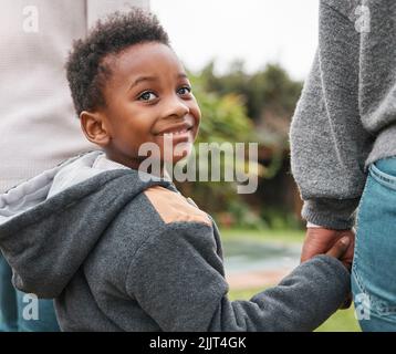 Allez-vous nous suivre dans une aventure. Un adorable petit garçon tenant les mains de ses parents tout en marchant ensemble à l'extérieur. Banque D'Images