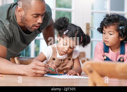 Faire preuve de créativité, c'est s'amuser. Un père se colorant dans une photo avec ses deux petites filles à la maison. Banque D'Images