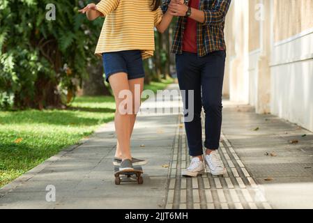 Image rognée d'un jeune homme enseignant à sa petite amie comment monter sur un skateboard Banque D'Images