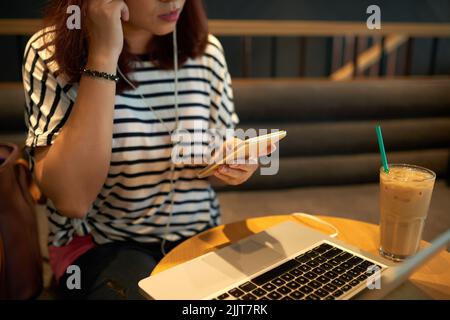 Image rognée d'une jeune femme écoutant de la musique sur son smartphone Banque D'Images
