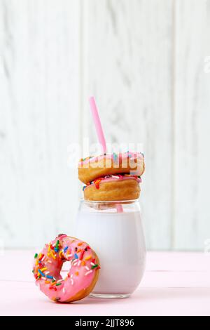 Un verre de lait avec des beignets savoureux sur fond blanc Banque D'Images